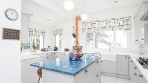A modern kitchen with a central island, white cabinetry, and a blue marble countertop. - Pine Lodge (Colwyn Bay)