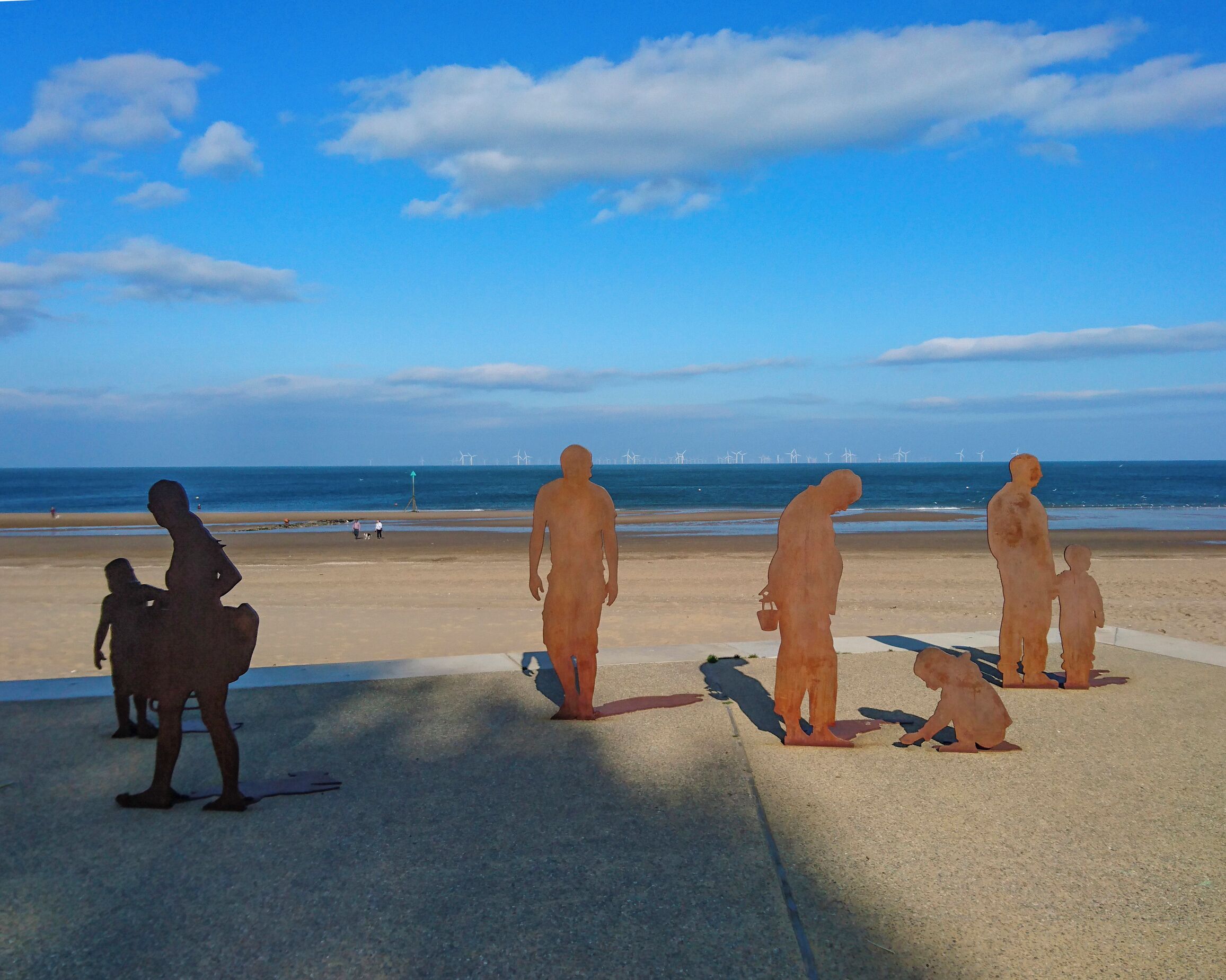 A beach with a row of human figures.