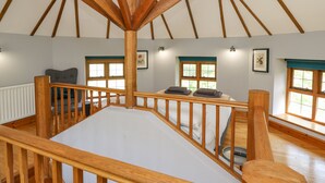 Une pièce spacieuse avec un plafond haut et des poutres en bois, comprenant un grand lit, une fenêtre avec vue et un radiateur.