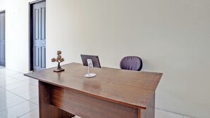 Een houten bureau met een smartphone op een standaard, een stoel en een klein decoratief object.