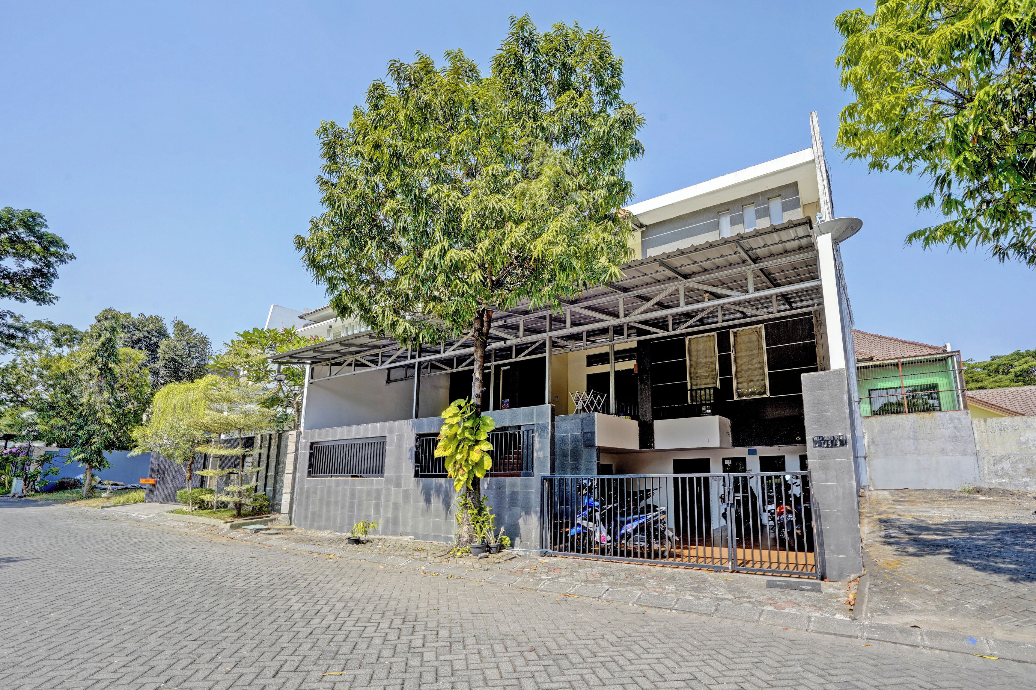 A two-story building with a covered parking area and a tree in front.