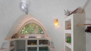 Um quarto aconchegante com arco, cozinha integrada, ventoinha e estante com livros.