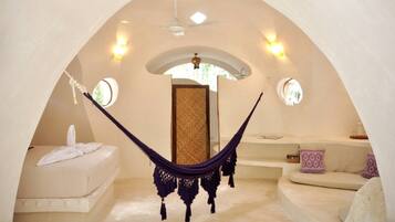 Una habitación acogedora de forma arqueada con una hamaca, un sofá y una cama.