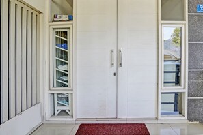 Enter a spacious room with a large double door, flanked by a shelving unit and a window.