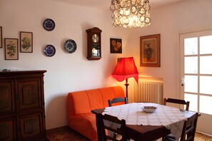 Een kamer met een eettafel, een bank, een kroonluchter en decoratieve borden aan de muur.