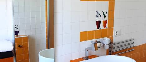 A bathroom with a white and orange color scheme, a large mirror, a white sink with a silver faucet, and a towel rack.