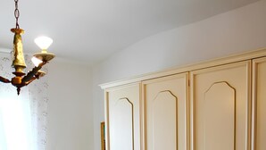Une chambre dotée d’une grande armoire, d’un fauteuil à bascule et d’un lit avec une literie à motifs floraux.