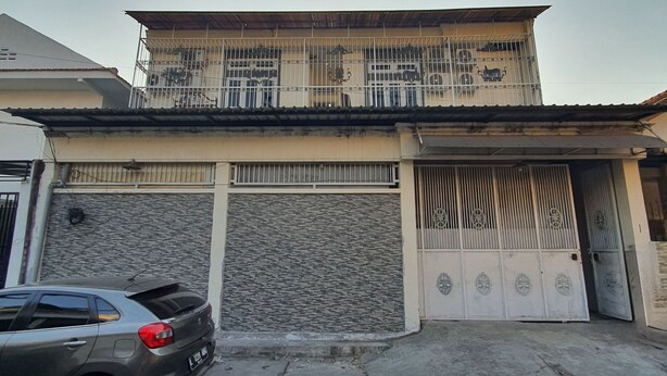 A two-story building with a balcony, a gated entrance, and a parked car. - OYO 93114 Salak Homestay Syariah (Surabaya)