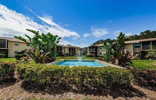Guests can enjoy a refreshing dip in the central pool surrounded by lush gardens and a tranquil fountain.