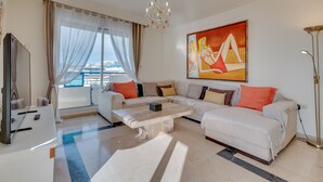 A modern living room with a sofa set, a coffee table, a TV, and a painting.
