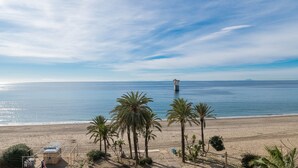 A beach with palm trees, a lifeguard tower, and a clear sky.