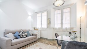 A modern living room with a sofa, a glass dining table, and a chair.