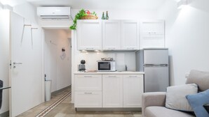 A compact kitchen with white cabinets, a microwave, and a refrigerator.