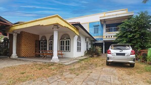 A two-story house with a covered porch, a car parked in front, and a checkered wall pattern. - Hotel O Arizona Homestay (Jambi)