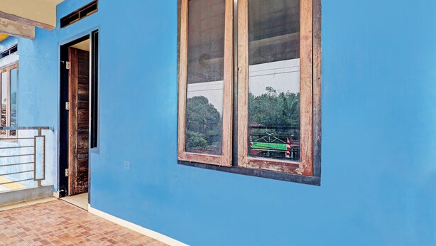 A room with a blue wall, a window with a wooden frame, and a tiled floor. - Hotel O Arizona Homestay (Jambi)