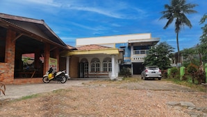 A building with a covered entrance and a parked motorcycle. - Hotel O Arizona Homestay (Jambi)