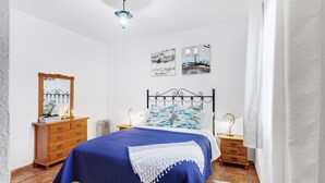 Ein Schlafzimmer mit einem Bett, einem Holzkleiderschrank, Nachttischen und Wandbildern.