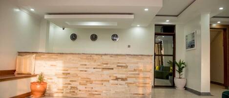 Una zona de recepción con pared de piedra, una planta en maceta y un reloj en la pared.