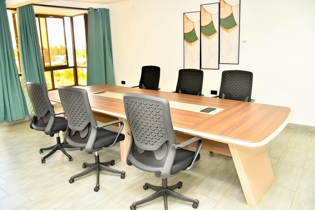 Una sala de conferències amb una taula de fusta llarga i sis cadires de despatx.