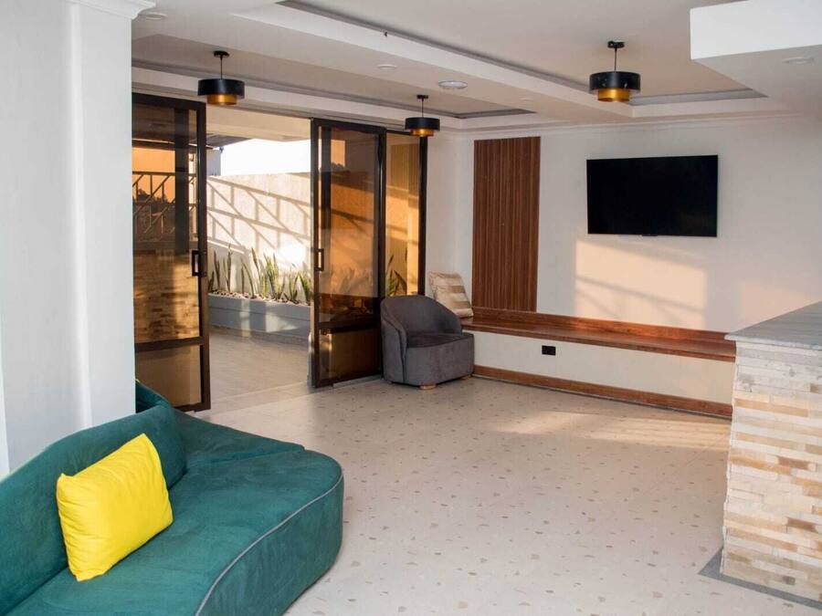 A modern living room with a green sofa, a grey armchair, and a TV mounted on the wall.