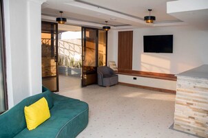 Una sala de estar moderna con un sofá verde, un sillón gris y un televisor montado en la pared.