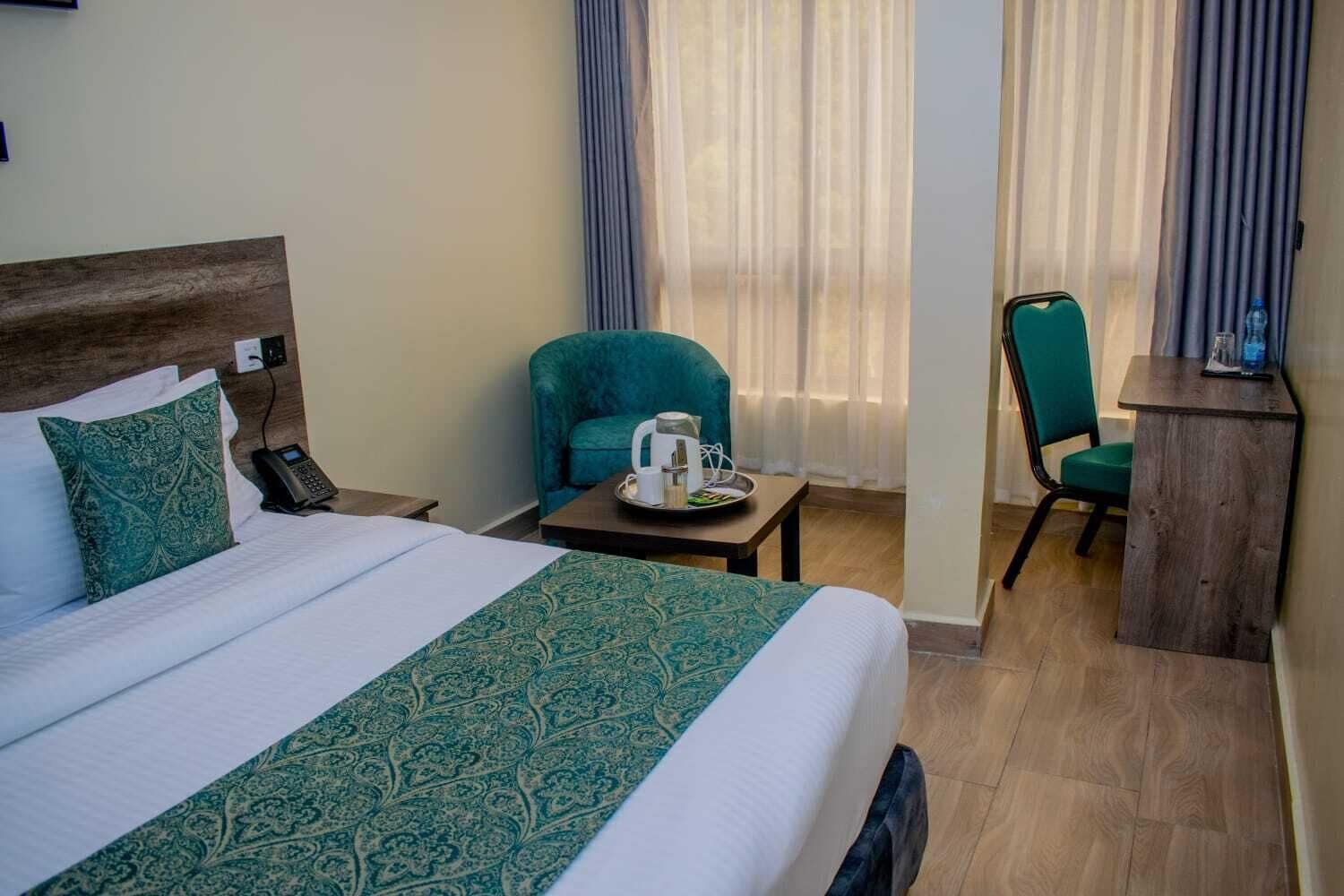 A hotel room with a large bed, a desk, a chair, and a coffee table.