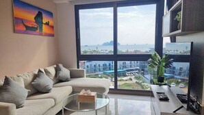 A modern living room with a large window, a sofa, a coffee table, and a painting.