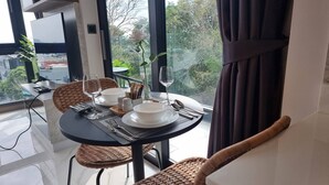 A dining area with a table set for two, a TV, and a view of the outdoors.