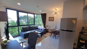 A modern living room with a sofa, coffee table, and dining area. - Ao405 - 1 Bdr Condo With Sea View, Ao Nang Beach (Krabi)