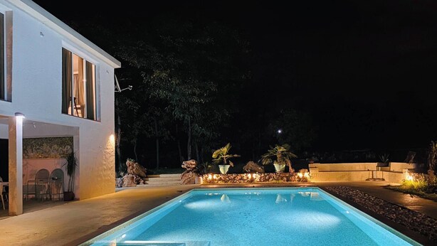 A swimming pool with steps leading into it, surrounded by a landscaped area with plants and a building with a balcony. - The Rock Star's Villa With Private Pool And Beach (Novo Selo)