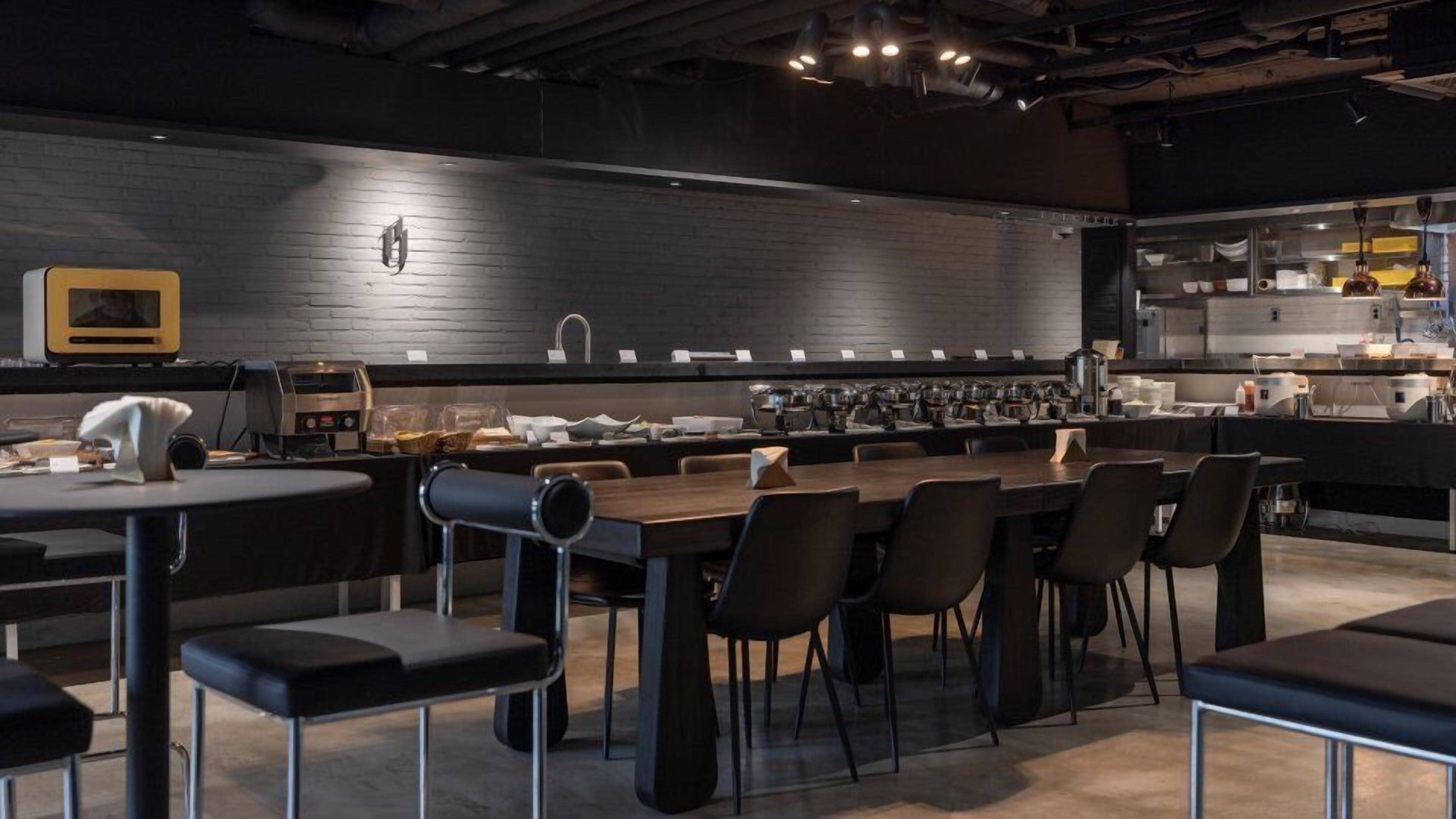 Um restaurante moderno com um balcão extenso, cadeiras pretas e uma máquina de café à vista.