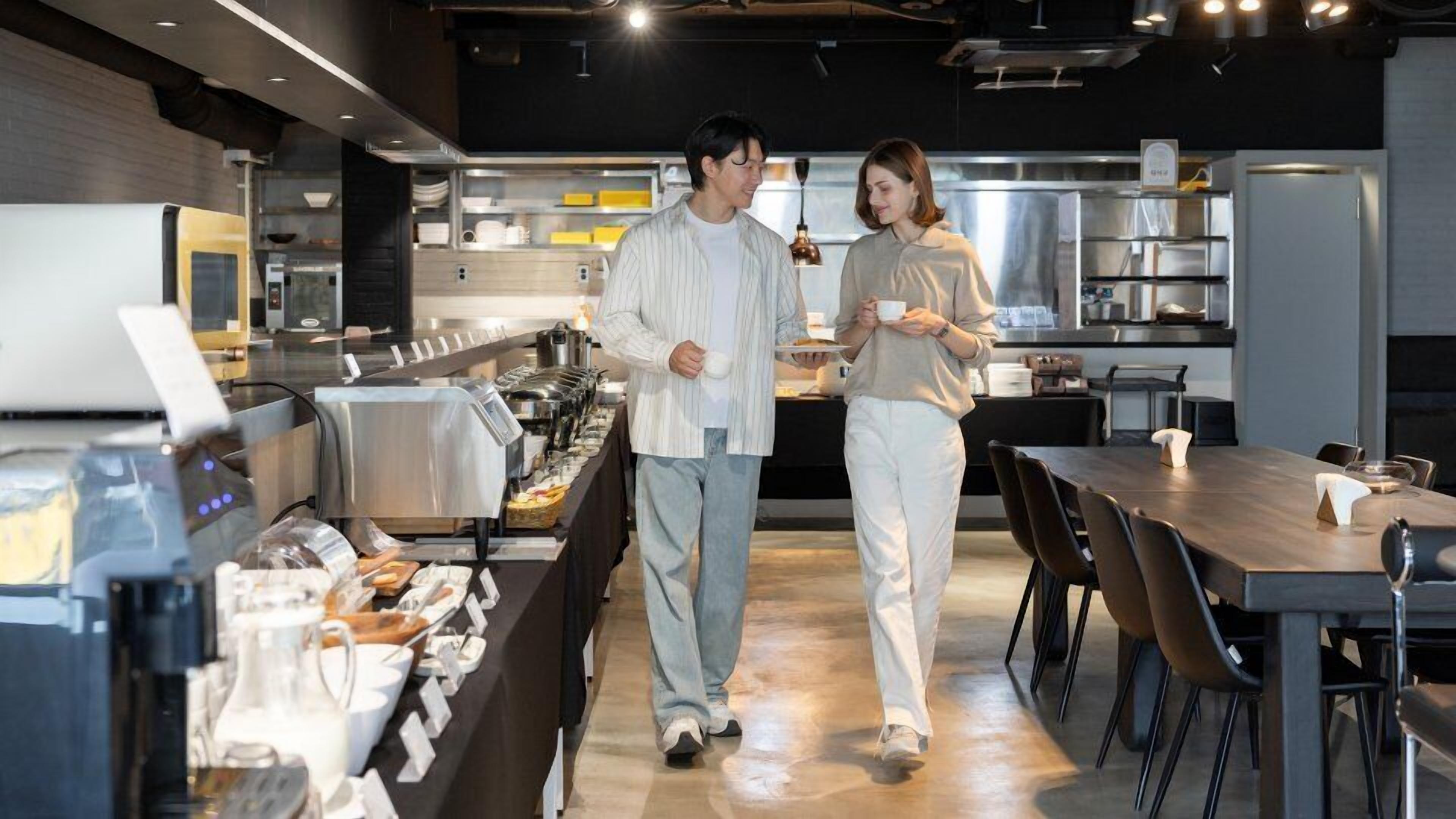 A modern kitchen with stainless steel appliances, a buffet setup, and a dining area with tables and chairs.