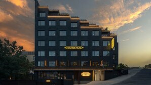 Un hotel moderno con fachada oscura, varios pisos y un letrero llamativo en la parte delantera.