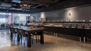 Una cafetería moderna con una barra alargada, varias máquinas de café y una pared de ladrillo.