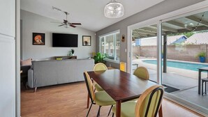 Eine moderne Küche mit Essbereich, Deckenventilator und Blick auf einen Gartenpool.