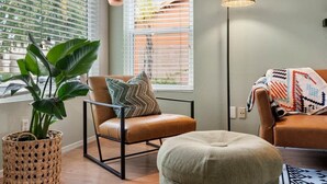 Ein modernes Wohnzimmer mit Ledersessel, Hocker und Stehlampe.
