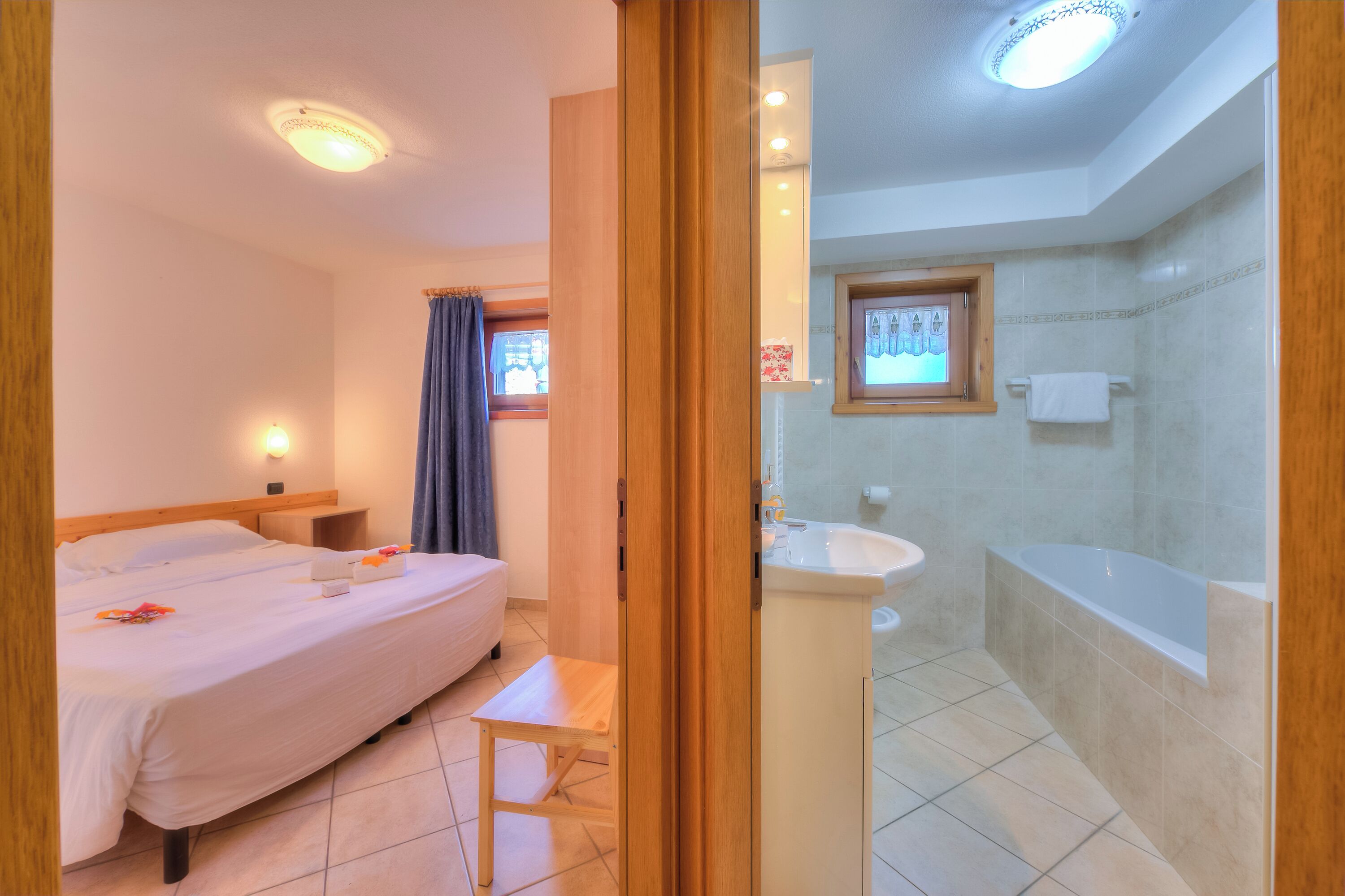 Hotellihuoneessa on sänky, yöpöytä ja pieni puujakkara. Kylpyhuoneessa on pesuallas, peili ja kylpyamme.