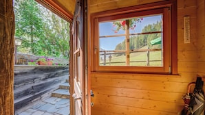A wooden cabin with a window view of a forest and a stone pathway. - Chalet Sciachilo’ Ski In-Ski Out 10m (Livigno)