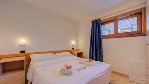 A hotel room with a bed, two bedside tables, a window with curtains, and a view of the outside. - Chalet Sciachilo’ Ski In-Ski Out 10m (Livigno)
