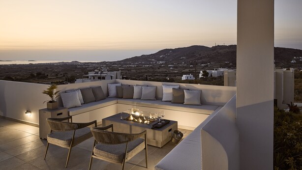 A rooftop terrace with a seating area, a fire pit, and a view of the landscape.