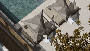 An aerial view of a pool area with three sun loungers and a clear swimming pool.