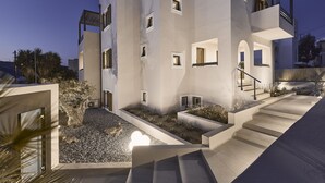 A modern multi-story building with a courtyard, outdoor staircase, and a pool area.