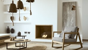 A modern living room with a fireplace, a rocking chair, and decorative items on shelves.