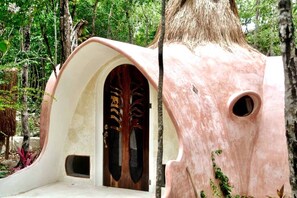 Unique treehouse design with curved entrance and intricate carvings, blending seamlessly into the surrounding forest.