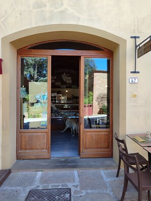 A wooden entrance with glass doors, a dog inside, and a sign indicating a restaurant.