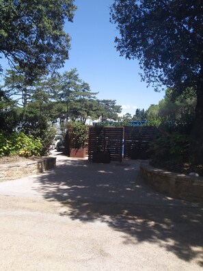 A paved pathway leading to a gated entrance with a brick wall and metal gate.