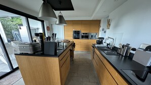 A modern kitchen with wooden cabinetry, a central island, and stainless steel appliances.