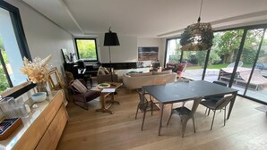 A spacious living area with a dining table, sofas, and a kitchen area with a wooden countertop.
