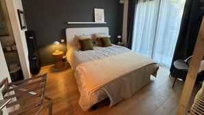 A bedroom with a bed, bedside tables, a chair, a wardrobe, and a window with curtains.