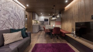 A modern kitchen with wooden cabinets, a dining area with a red bench, and a large flat-screen TV mounted on the wall. - Fliana Residenz (Ischgl)
